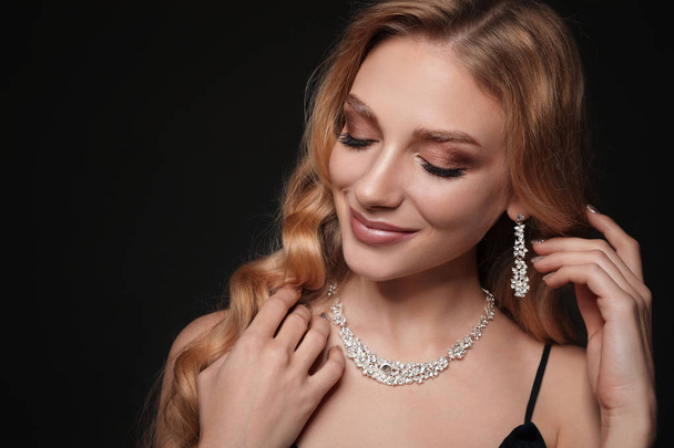 Beautiful young woman with elegant jewelry on dark background. Space for text - Fotografie, Obrázek