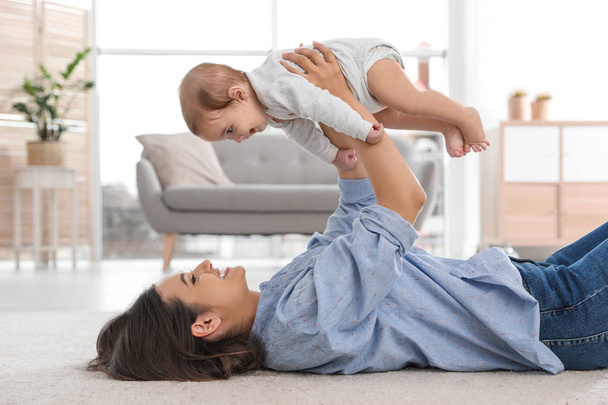 Happy young mother playing with baby on floor at home - Фото, зображення