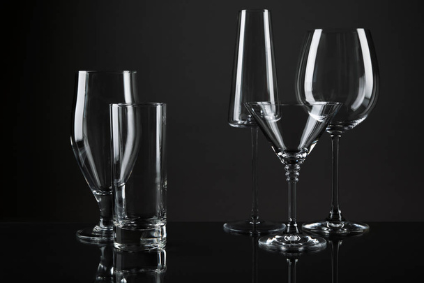Empty glasses for different drinks on dark background - Foto, imagen