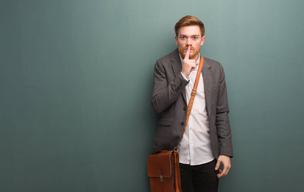 Young redhead business man keeping a secret or asking for silence - 写真・画像