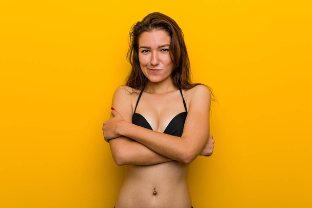 Joven mujer europea vistiendo bikini frunciendo el ceño con desagrado, mantiene los brazos cruzados
. - Foto, imagen