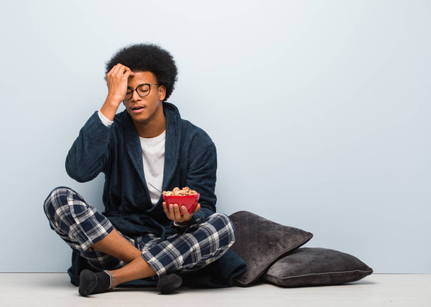 Молодой черный мужчина сидит и завтракает взволнованным и подавленным
 - Фото, изображение