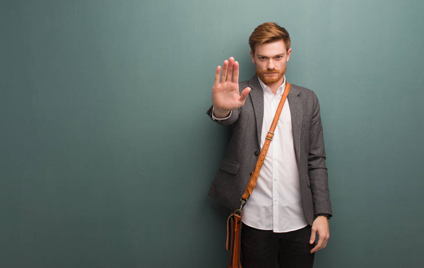 Νεαρός κοκκινομάλλης επιχειρηματίας που βάζει χέρι μπροστά - Φωτογραφία, εικόνα