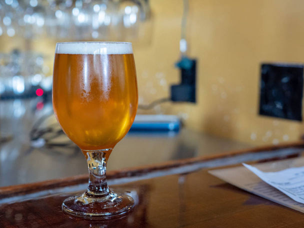 Glas bleke bier zittend op de bovenkant van de bar met schuim - Foto, afbeelding