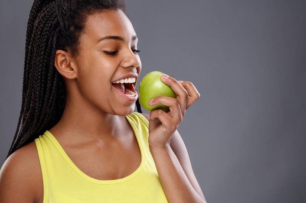Afro-American female biting apple - Фото, зображення