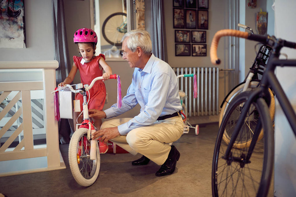 smiling grandfather and child choosing bicycle in bike shop - Foto, Imagen