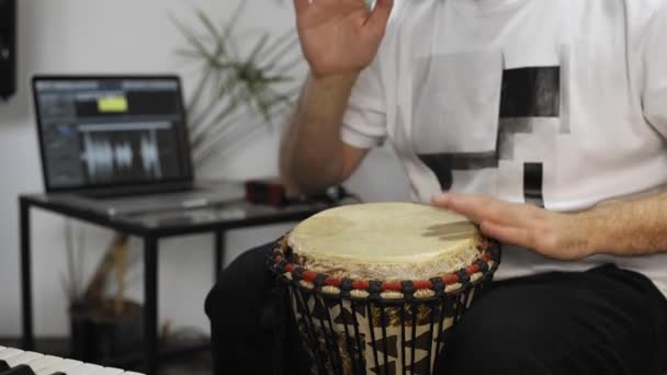 Close up of professional musician recording djembe drum instrument in digital studio at home.  He is surrounded with instruments and midi controller. Music production concept.  - Footage, Video