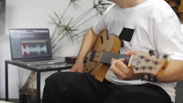 Close up of professional musician recording electric guitar in digital studio at home.  He is surrounded with instruments and midi controller. Music production concept.  - Filmmaterial, Video