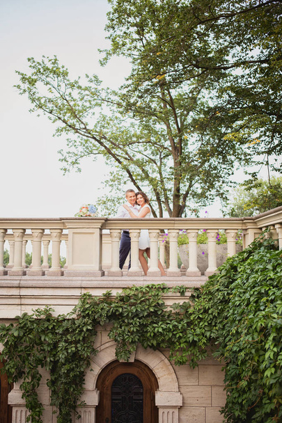 beautiful young bride and groom walking and posing on marble stairs on garden view background - Foto, imagen