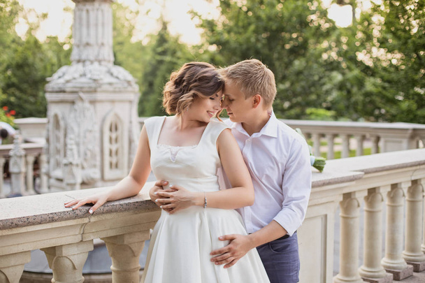 beautiful young bride and groom walking and posing on marble stairs on garden view background - Fotografie, Obrázek