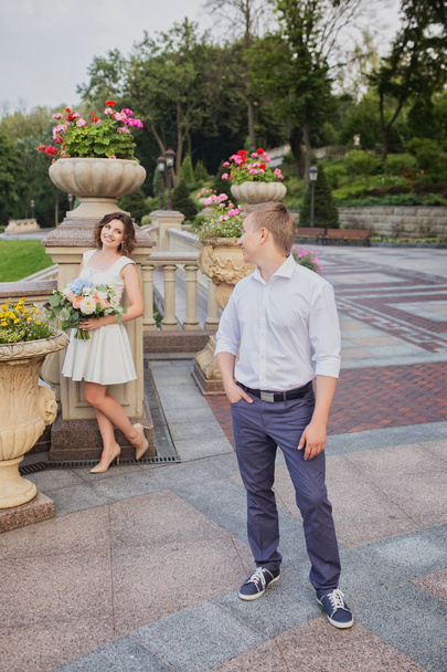 beautiful young bride and groom walking and posing on marble stairs on garden view background - Fotografie, Obrázek