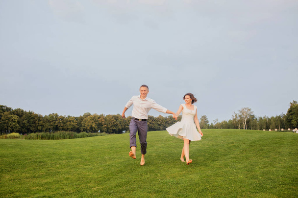 beautiful young groom and bride walking on green park with lush green grass view background - Foto, afbeelding