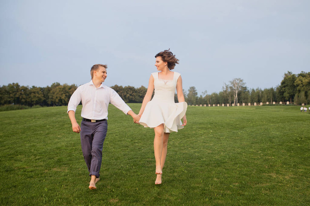 beautiful young groom and bride walking on green park with lush green grass view background - 写真・画像