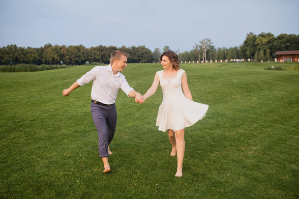 beautiful and cute young groom and bride walking on green garden with lush green grass view background - Foto, immagini