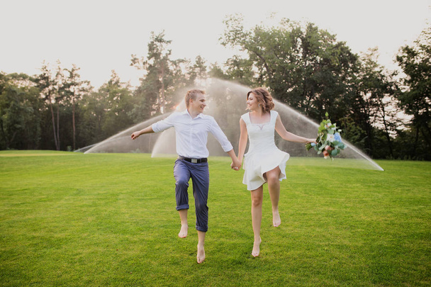 beautiful and cute young groom and bride walking on green garden with lush green grass view background - Foto, Imagen