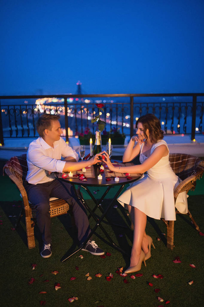 beautiful boy and girl celebrating love date on bridge on night city view background - Foto, afbeelding