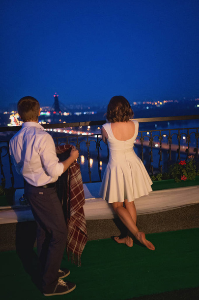 amazing young couple of lovers standing on bridge on night city view background - 写真・画像