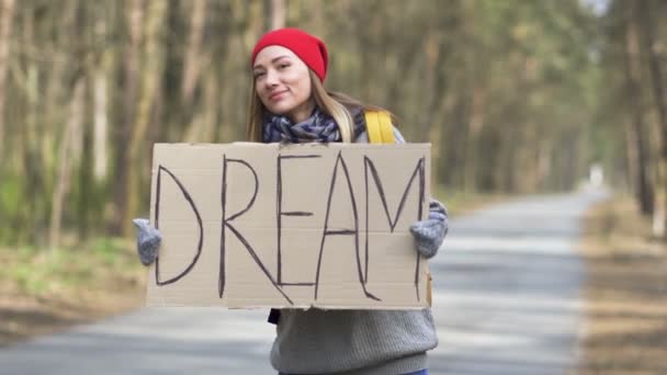 Joven autoestop mujer ir en la carretera con el sueño del cartel. Vista trasera
 - Imágenes, Vídeo