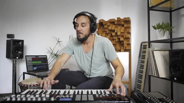 Profi zenész felvétel MIDI billentyűzet a digitális stúdió otthon. Ő veszi körül hangszerek és MIDI kontroller. Zenei produkciós koncepció.  - Felvétel, videó