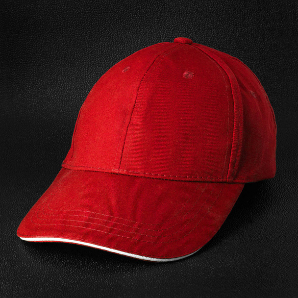Κόκκινο καπάκι σκούρο φόντο. Πρότυπο καπέλο μπέιζμπολ σε πλευρική όψη. - Φωτογραφία, εικόνα
