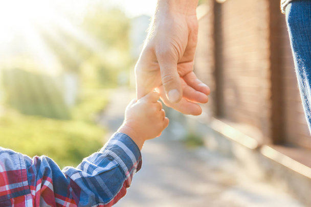 ο γονέας κρατώντας το χέρι του παιδιού με ένα ευτυχισμένο υπόβαθρο - Φωτογραφία, εικόνα