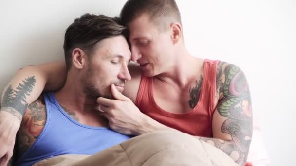 Caucasian gay couple is lying on bed, hugging and kissing - Séquence, vidéo