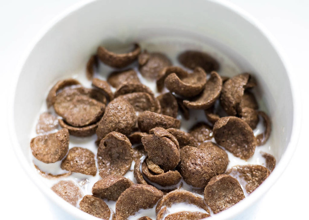 Schokolade Müsli mit frischer Milch in weißen Schüssel Hintergrund. köstliche Kakao-Cornflake. - Foto, Bild