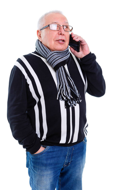 alter älterer Herr in Pullover, Schal und Brille, der mit dem Handy spricht, isoliert vor weißem Hintergrund - Foto, Bild