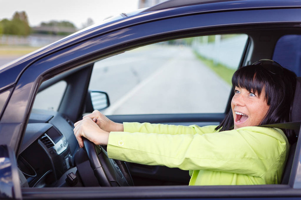 Scared and surprised woman with big eyes shouts driving the car - outdoors - Photo, Image