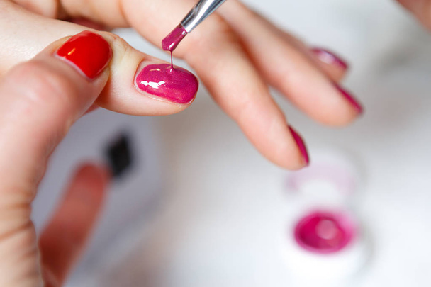 Manicure in process - Beautiful manicured woman's nails with red nail polish. The industry of beauty and nail care, beauty salons, soft focus - Foto, Imagen