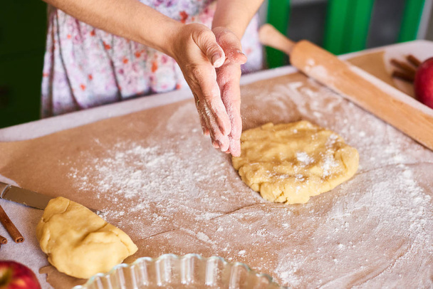 Kädet työskentelevät taikinan valmistelu resepti leipää. Naiskäsi tienaa rahaa pizzaa varten. Naisen kädet pyörittävät taikinaa. Äiti rullaa taikinaa keittiön pöydällä valssaustapin kanssa
 - Valokuva, kuva