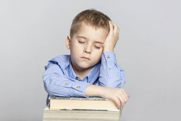 Schoolboy sleeps on the books for doing homework. Close-up. Gray background. - Foto, afbeelding