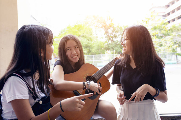 grupo de asiático adolescente de pie al aire libre plying español guitarra a
 - Foto, Imagen