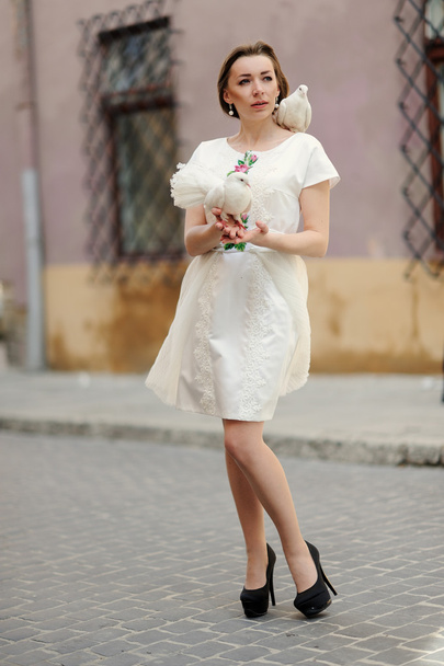 Cute girl with dove in the hand posing on a city street - Фото, изображение