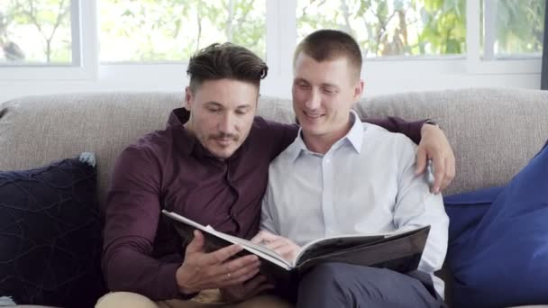 Caucasian gay couple is reading book at home - Felvétel, videó
