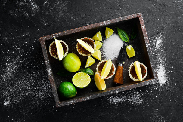 Gold tequila with lime and salt on black stone background. Top view. Free space for your text. - Photo, image