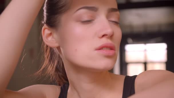 Closeup shoot of young attractive athlete female working out and sweating in the gym indoors - Filmati, video
