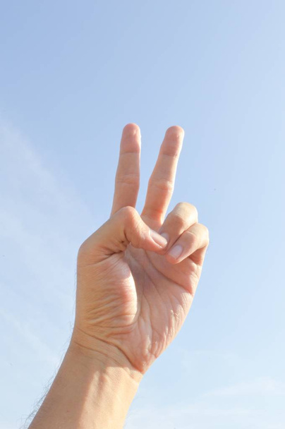 Рука з двома пальцями або знак перемоги на блакитному небі
 - Фото, зображення