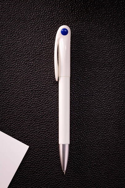 Μπλε στυλό και λευκή κάρτα σε σκούρο φόντο. Κενό στυλό διαρκείας για το σχέδιό σας. - Φωτογραφία, εικόνα