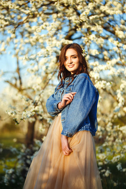 Portrait of a beautiful bride. Wedding concept. Stylish wedding. Great sunset light. She is wearing a blue denim jacket, dress. Spring blooming garden. - Photo, Image