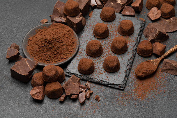 classic chocolate truffles and pieces of chocolate on dark concrete background - Foto, Imagem