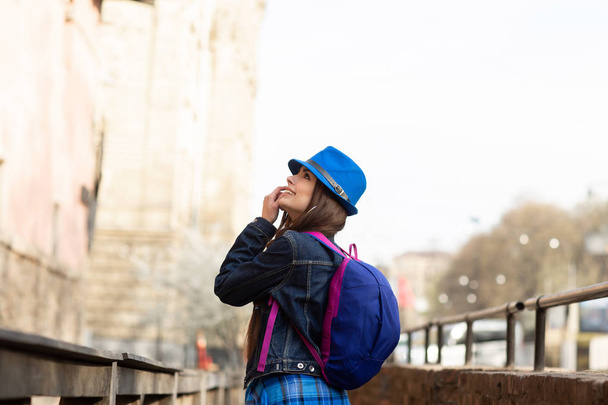 Young stylish woman walking on the old town street, travel with backpack and blue hat. Ukraine, Lviv - Photo, image