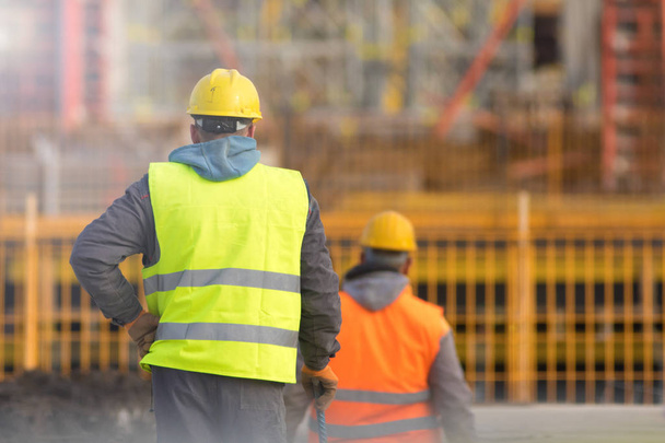 Deux ouvriers en jaune et orange sur le chantier
 - Photo, image