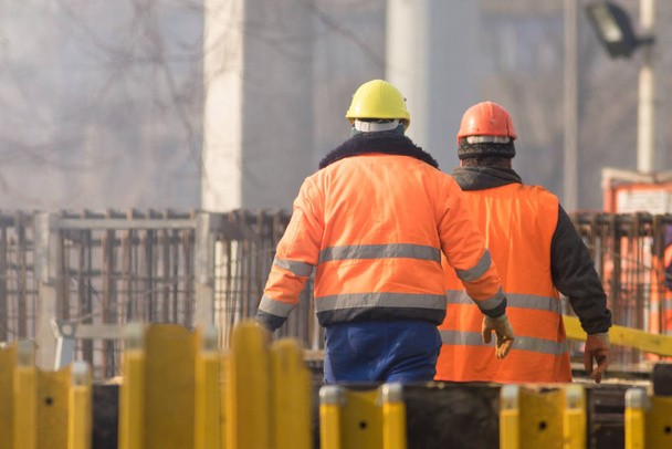 Dos trabajadores en naranja en el área de reconstrucción
 - Foto, Imagen