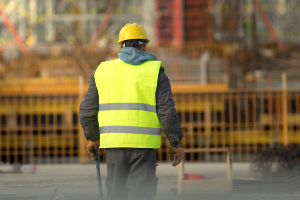 İnşaat alanında çalışan sarı elbiseli bir işçi. - Fotoğraf, Görsel