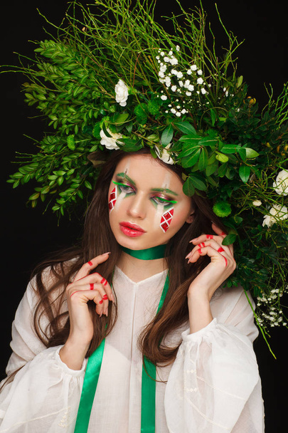 Portrait of a beautiful woman in a white dress with a green ribbon and with branches on her head. Creative makeup - Φωτογραφία, εικόνα