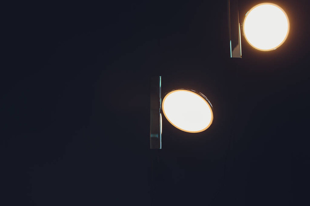 Two incadescent light bulbs in an industrial lamp. Dark environment. Concept of idea. Copy space on the left. - 写真・画像