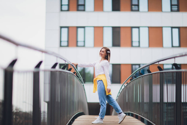 Hipster girl wearing blank white t-shirt and jeans posing against street road, minimalist urban clothing style. - Foto, Imagen