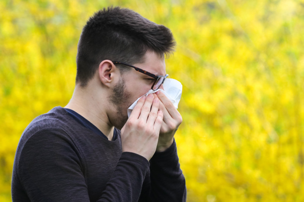 Boy with polen allergy over flowers is sneezing - Photo, Image