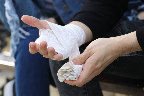 Close up of bandaging injured hand after an accident - Photo, Image